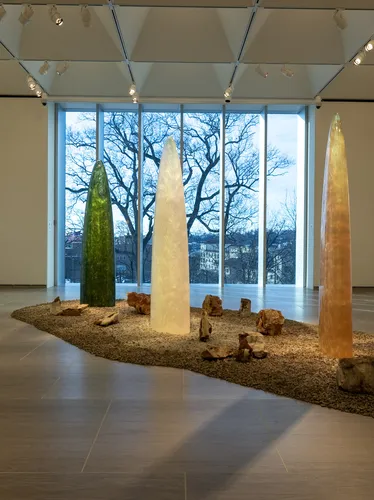 Standing sculptures shaped like colorful, translucent rockets and amorphous wall pieces that refract light.