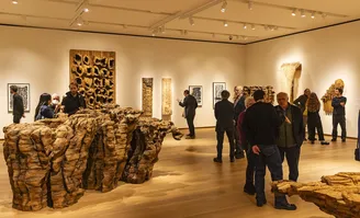 Photo of people in an art gallery viewing sculptures in Ursula von Rydingsvard: states of becoming at the Bruce Museum